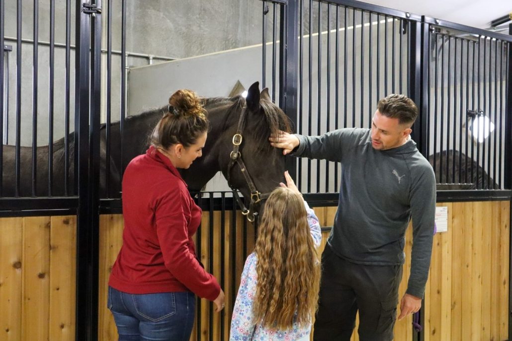 Image of what appears to be father and daughter participants petting a horse.